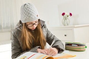 Teenaged girl going homework in hard condition - heating is not working during winter time.