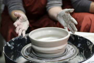 Fototapeta na wymiar Hands of a Potter creating the clay. Vessel on the Potter's wheel.