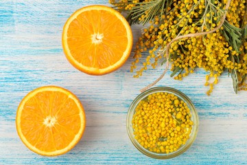 Beautiful flowers of yellow mimosa and orange on a blue wooden background. top view. close-up