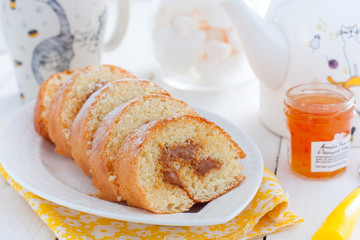 Biscuit roll with boiled condensed milk on a white plate, selective focus