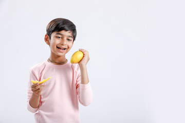 Cute indian/Asian little boy eating Mango with multiple expressions. isolated over white background