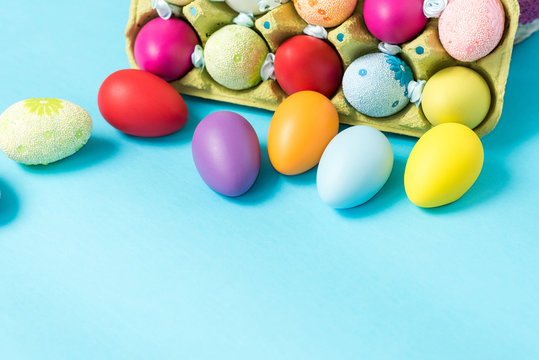 Easter eggs are painted in bright colors, lie in a cardboard eco-packaging. Blue background. Easter ideas. Space for text. Egg eco tray. Happy easter.