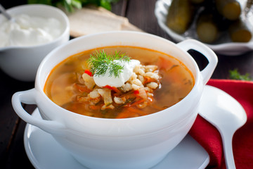 Soup with pickled cucumbers and pearl barley - rassolnik on a wooden background,horizontal