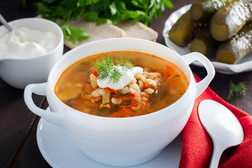 Soup with pickled cucumbers and pearl barley - rassolnik on a wooden background,horizontal