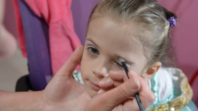 Do makeup to child. The mother paints the face of a little girl.