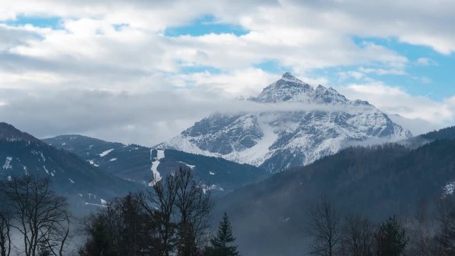 Time lapse of Serles in Tyrolean Alps in morning light in winter. Cloudy weather with fog in the valley. Snow on the mountain.