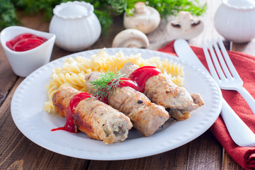 Small pork rolls - pork fingers, with mushrooms on a white plate with pasta and ketchup, horizontal