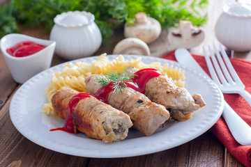 Small pork rolls - pork fingers, with mushrooms on a white plate with pasta and ketchup, horizontal