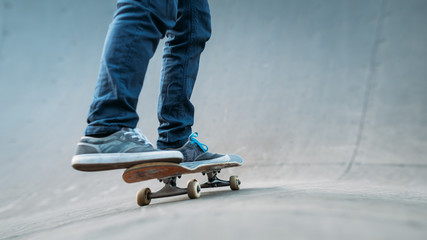 Urban skater practice. Man riding skateboard. Legs in jeans shot. Skate park ramp. Copy space.