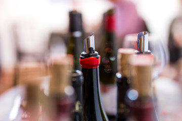 open wine bottles, flexible wine pourer, glasses, corks with blurred background at the wine tasting event