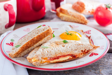 Breakfast with scrambled eggs and closed hot sandwich with cheese, tomatoes and sausage, horizontal