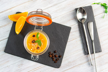 Traditional Italian Panna cotta with orange and mint on a jar. Homemade dessert on a wooden table,...