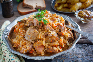 Braised cabbage with turkey thigh meat on a wooden table, horizontal