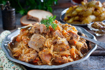Braised cabbage with turkey thigh meat on a wooden table, horizontal