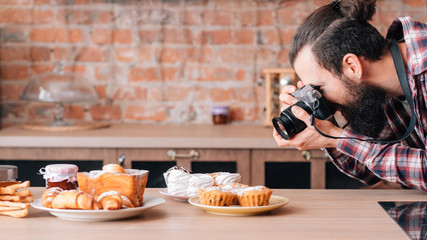 Fototapeta na wymiar Food photographer. Dessert assortment. Man with camera taking photos of fresh homemade pastries. Copy space.