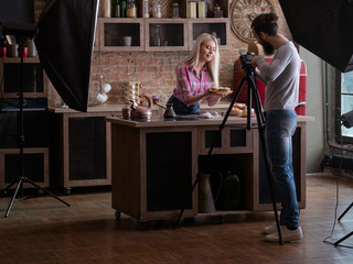 Fototapeta na wymiar Homemade cooking. Baking hobby. Backstage photography. Man shooting woman with fresh cakes and pastries.