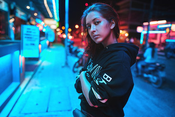 Neon close up portrait of young woman wear hoodie. night city street shot