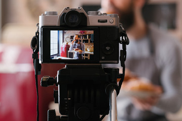 Bakery business. Culinary vlog. Podcast shooting. Man in apron with fresh pastries. Camera screen.