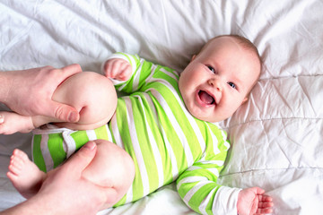 The little newborn girl lies on the bed. Dad does her masses. The child has overweight, obesity.