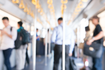 Blurry image, people standing in a public transportation bus with poles and handgrip