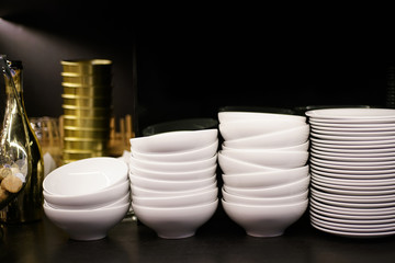 White plates and bowls on black glossy shelf