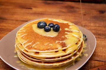 Pancakes with blueberries and honey on the dark brown wooden background