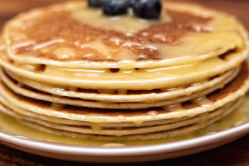 Pancakes with blueberries and honey on the dark brown wooden background
