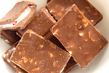 Broken dark chocolate pieces pile from top view on white background