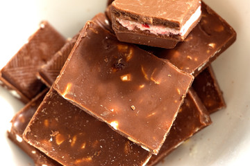 Broken dark chocolate pieces pile from top view on white background