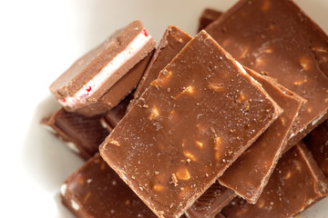 Broken dark chocolate pieces pile from top view on white background