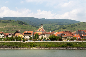 Fototapeta na wymiar village on the banks of the Danube river in Austria with green mountains in the background