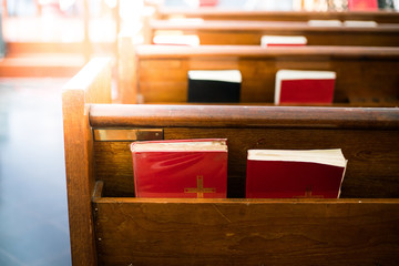 Bibles in wooden bench compartment in church, church service for Christian