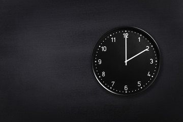 Black wall clock showing two o'clock on black chalkboard background. Office clock showing 2am or 2pm on black texture