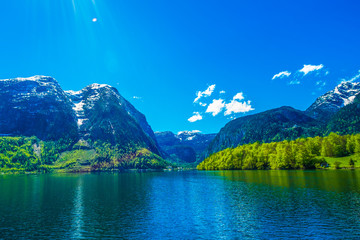 Naklejka na ściany i meble Mountain and amazing Alpine lakes, Hallstatt, Austria with blue sky and sun ray. Lens flare from the upper left corner