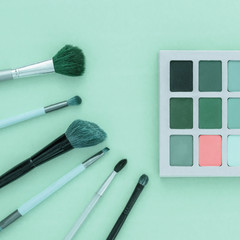 Cosmetic shadows and a set of professional brushes on a turquoise monophonic background, minimal, art, design. Concept - not like everyone else