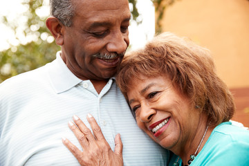 Senior black husband and wife embracing outdoors, close up