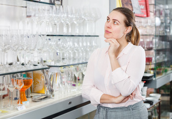 Woman customer choosing wineglass in the tableware store