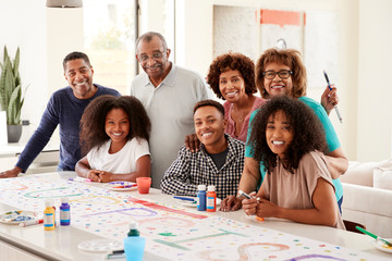 Three generation black family making a sign for surprise party smiling to camera,close up