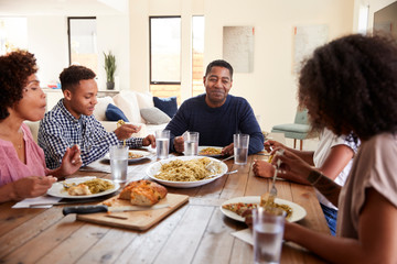 Middle aged black man sitting at the table eating dinner with his wife and family, close up