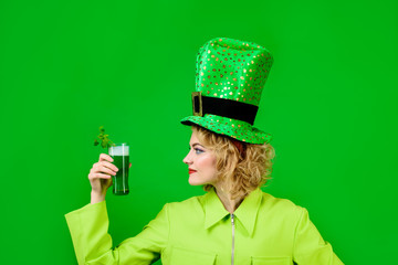 Beautiful woman in green hat with beer. Happy girl in leprechaun hat drinks green cocktail. St....