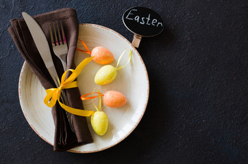 Festive table setting for holiday Easter dinner on dark table.