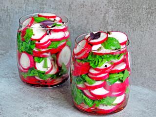 Fototapeta na wymiar Radish salad with spinach in a jar. Fitness salad in the jar. Fresh radishes and fresh chopped spinach leaves. Vegetable salad in a jar to go.