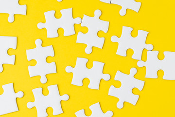 White jigsaw puzzle on solid yellow background metaphor solution to solving business problem, creativity, choice or teamwork concept