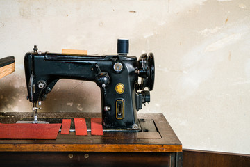 Old vintage pedal sewing machine with rustic grungy cement wall