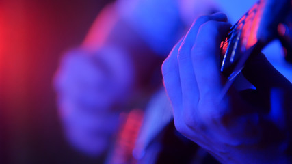 Young musician playing guitar in neon lighting