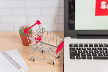 Small red shopping cart or trolley on laptop keyboard, Technology business online shopping concept.