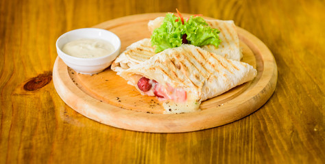 Meat wrapped with lavash burrito. Restaurant meal traditional cuisine. Burrito tortilla served wooden board. Restaurant food concept. Lavash burrito stuffed meat sausage and cheese sauce served salad