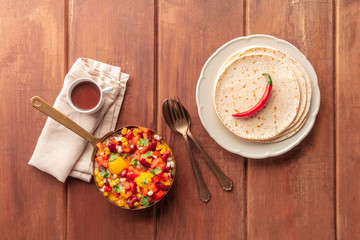 Mexican breakfast food. Huevos rancheros, fried eggs, shot from the top with pico de gallo salad, hot chocolate, and tortillas on a dark rustic wooden background with copy space