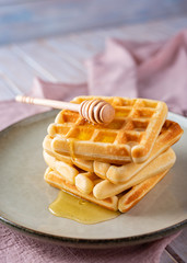 Waffles with honey on a light background.