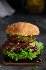 Homemade fresh beef burger on wooden board in dark mood photo style.